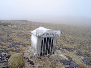 La cumbre tiene además del monolito, diferentes objetos metálicos.